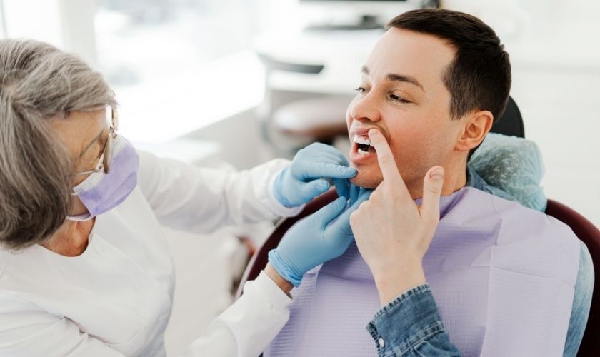 Dentist examining patient's mouth during oral examination at dental office.